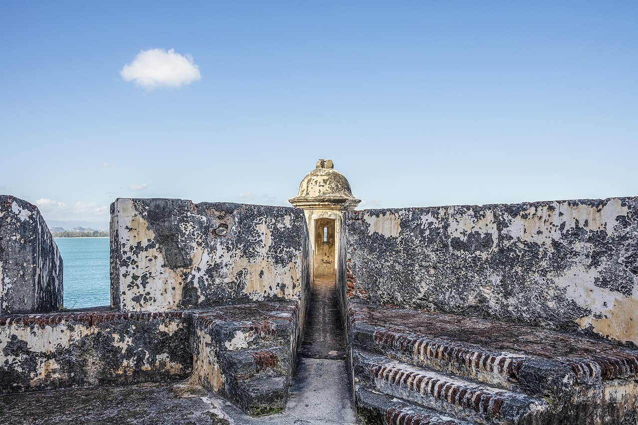 A stone sentry box on the weathered ramparts of Castillo San Felipe del Morro with the sea beyond