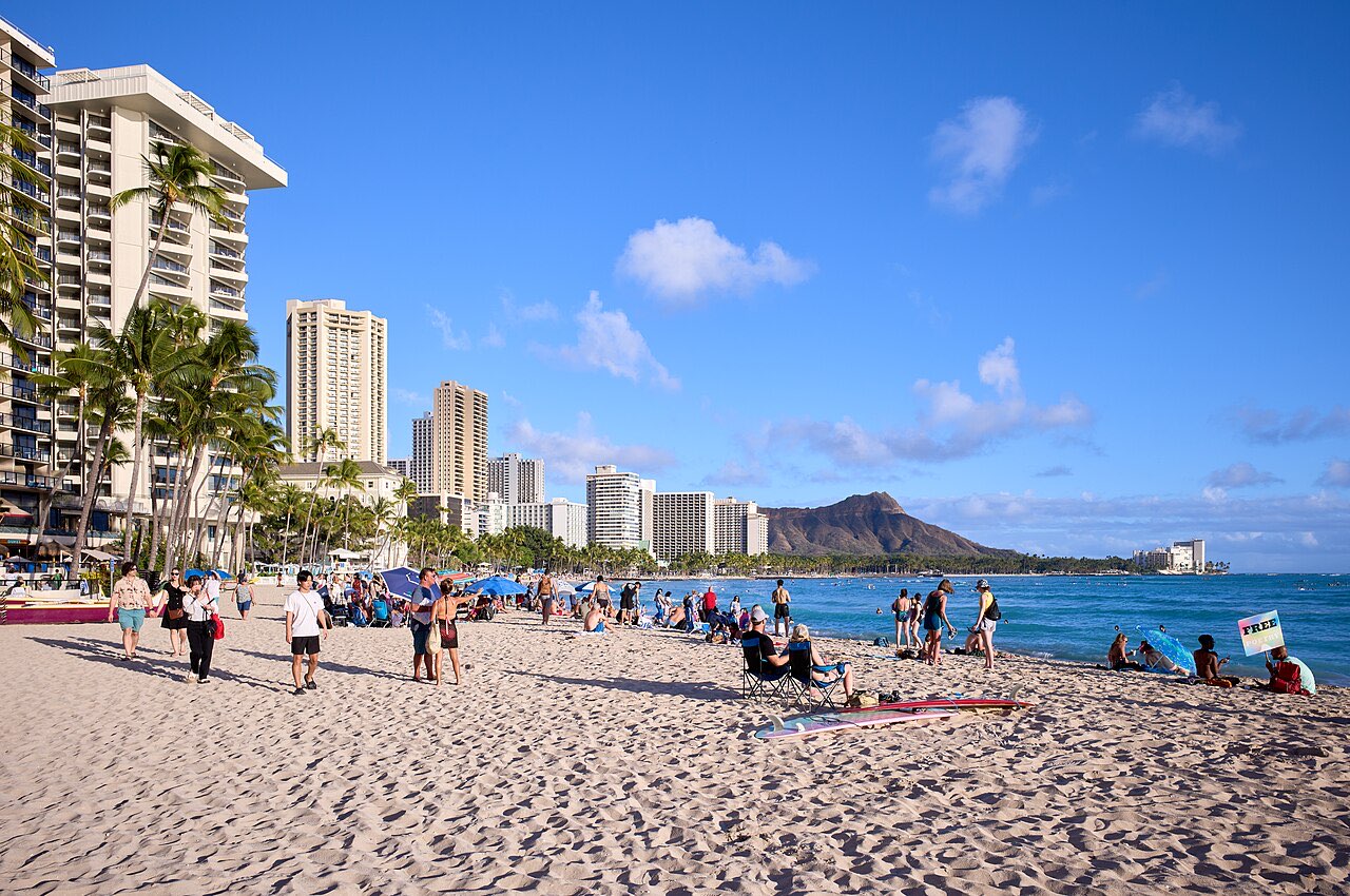 Waikiki Beach in Honolulu with hotel towers along the sand and Diamond Head crater in the distance